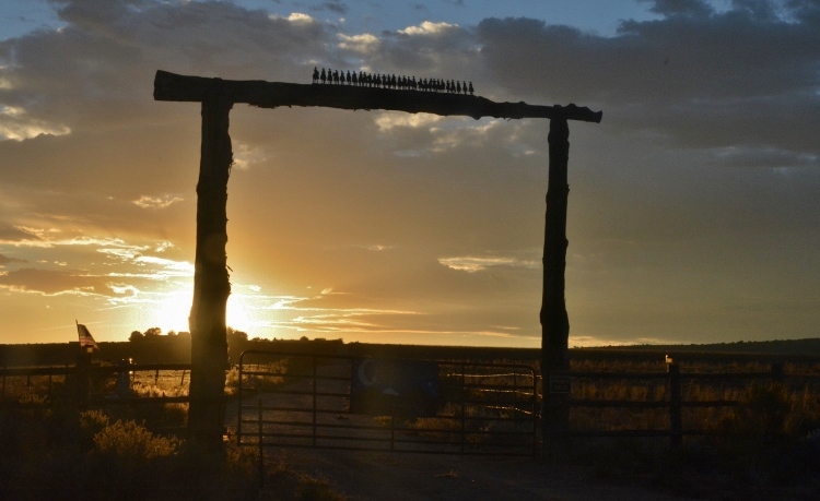 gate entranch to ranch with cowboys on horses